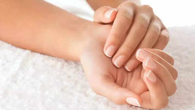 Woman examining her fingernails, suggesting concern about weak nails.